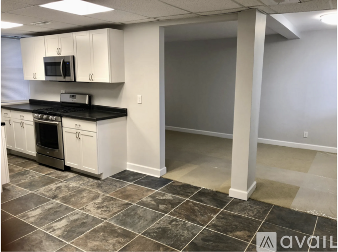 A kitchen with white cabinets and black countertops.