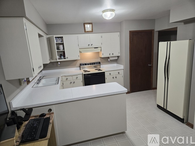 A kitchen with white cabinets and a black keyboard on a desk.