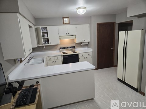A kitchen with white cabinets and a black keyboard on a desk.