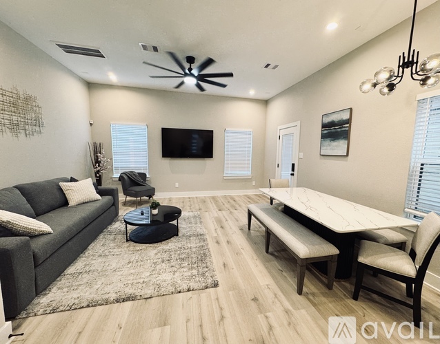 A modern living room with a grey couch, a wooden table, and a ceiling fan.