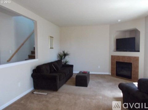 A living room with a black couch and a fireplace.