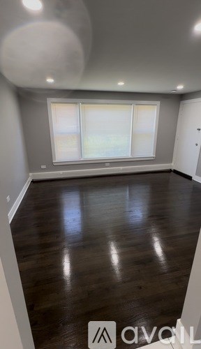 A room with wooden flooring and a window with blinds.