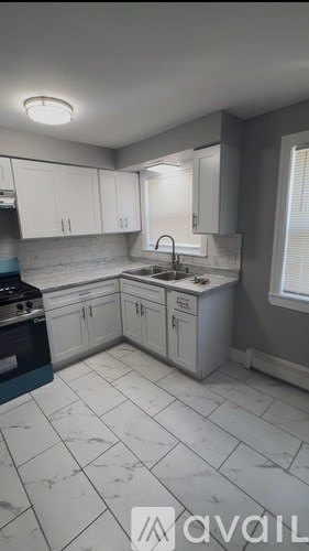 A kitchen with white cabinets and a marble floor.
