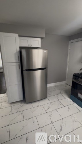 A kitchen with a stainless steel refrigerator and white cabinets.