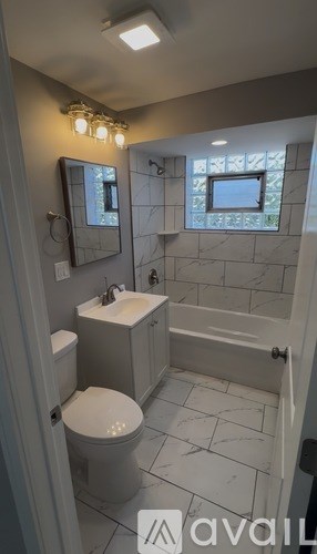 A bathroom with a toilet, sink, and mirror.