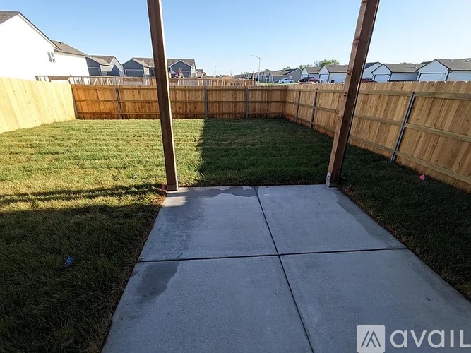 A backyard with a concrete walkway and wooden fence.