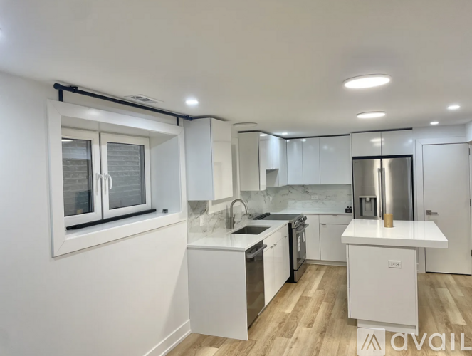 A modern kitchen with white cabinets and a wooden floor.