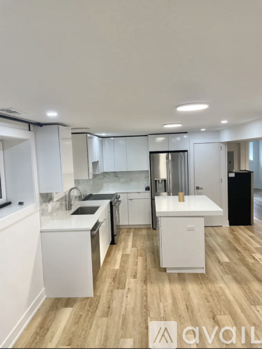 A modern kitchen with white cabinets and a wooden floor.