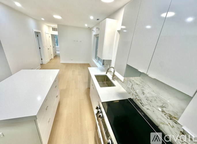 A modern kitchen with white cabinets and a marble backsplash.