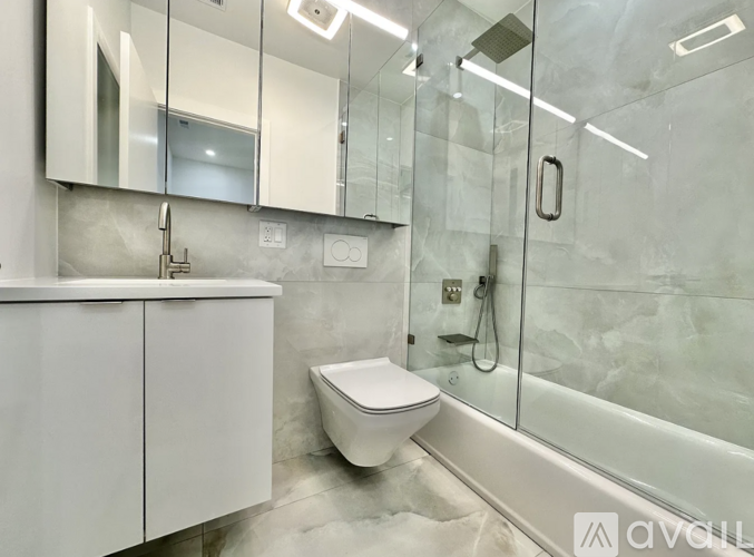 A white toilet sits in a modern bathroom with a glass shower area.
