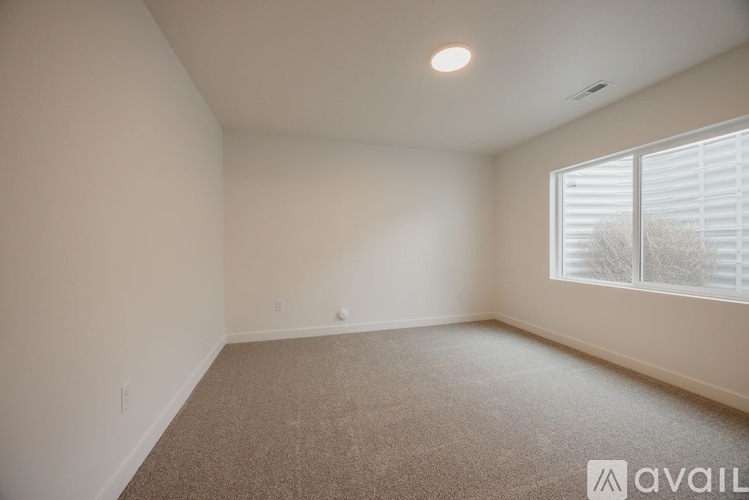 A room with a carpeted floor and a window with blinds.