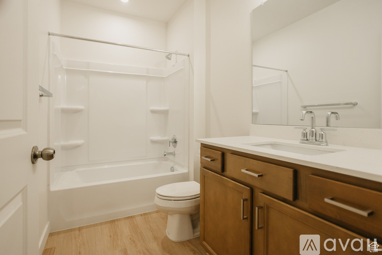 A white bathroom with wooden floors and a white toilet.