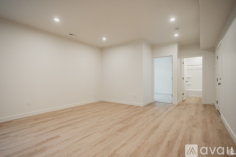 A spacious room with wooden flooring and white walls.