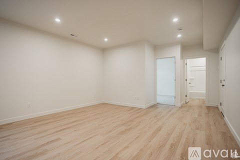 A spacious room with wooden flooring and white walls.