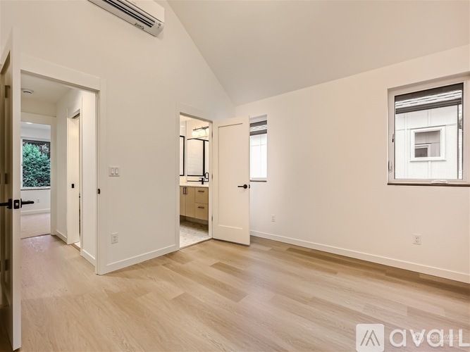 A spacious room with light wood flooring and white walls.