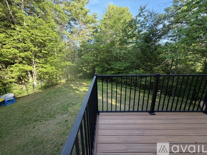 A deck with a black railing overlooks a grassy area with trees.