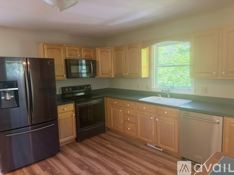 A kitchen with wooden cabinets and a black refrigerator.