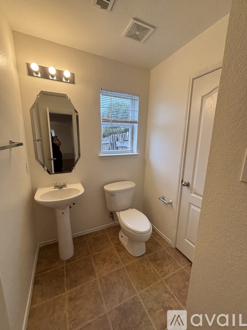 A bathroom with a toilet, sink, and mirror.