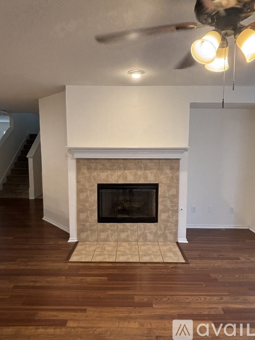 A living room with a fireplace and a fan.