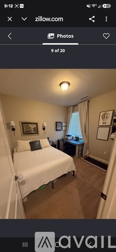 A bedroom with a white bed and a window with curtains.