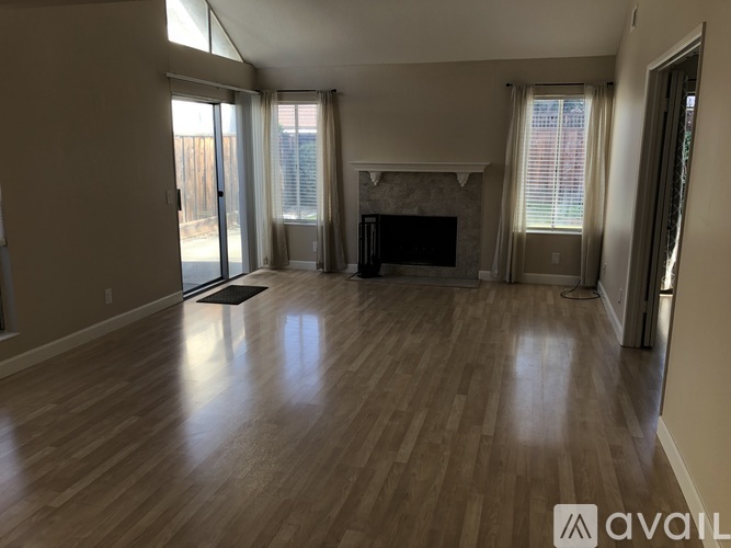 A spacious living room with wood flooring and a fireplace.