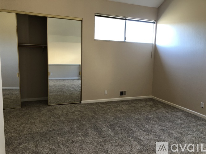 A room with a grey carpet and a large mirror on the wall.