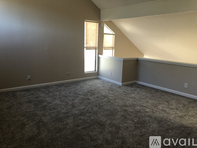 A room with a carpeted floor and a window with blinds.