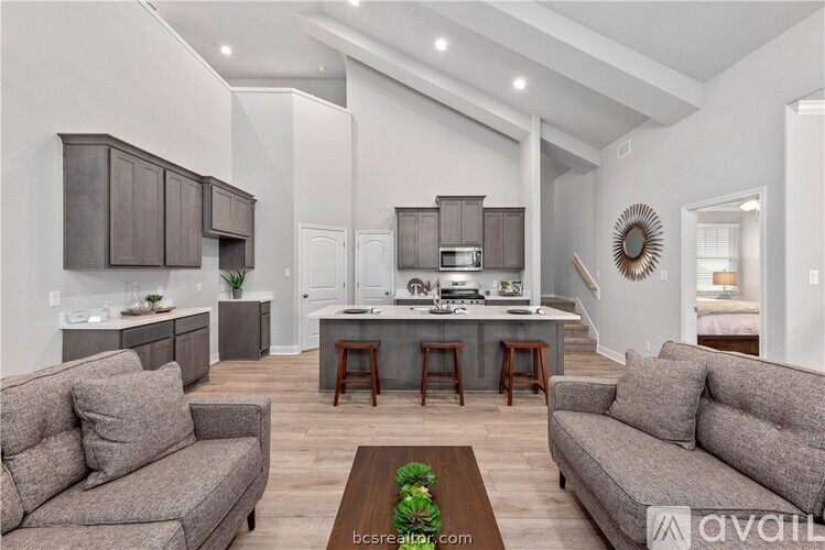 A modern kitchen with a breakfast bar and a living room with two couches.