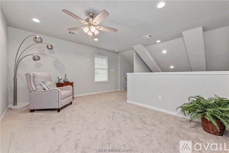 A spacious room with a ceiling fan, carpeted floor, and a chair.