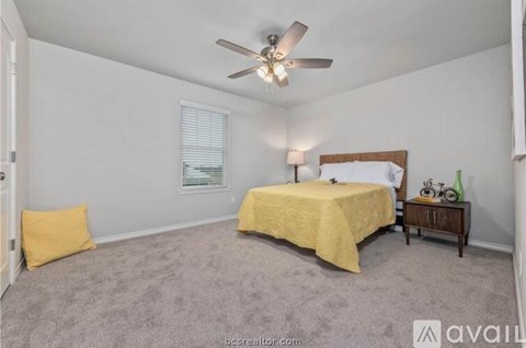 A bedroom with a bed, a ceiling fan, and a nightstand with a bicycle on it.