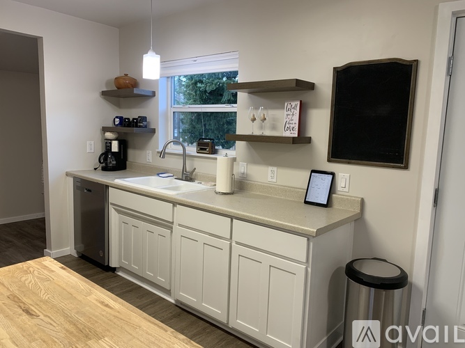 A kitchen with white cabinets and a wooden floor.