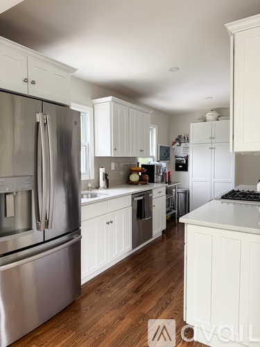 A modern kitchen with white cabinets and a stainless steel refrigerator.