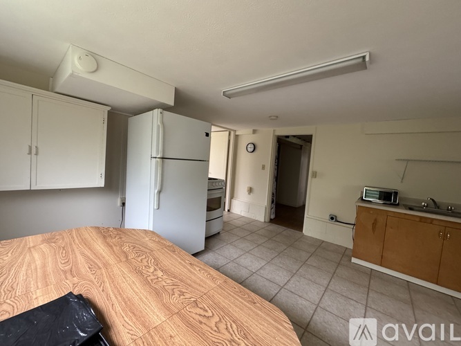 A kitchen with a fridge, cabinets, and a wooden table.