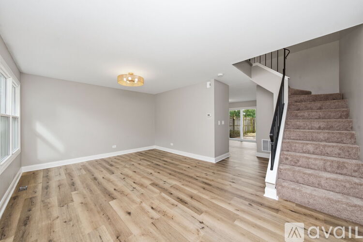 A spacious room with wooden flooring and a staircase leading to another room.