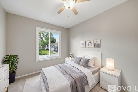 A well-lit bedroom with a large bed and a ceiling fan.