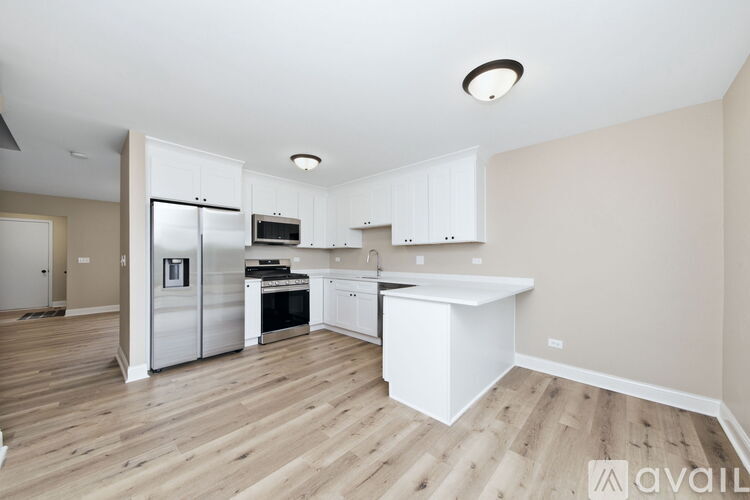 A kitchen with white cabinets and a wooden floor.