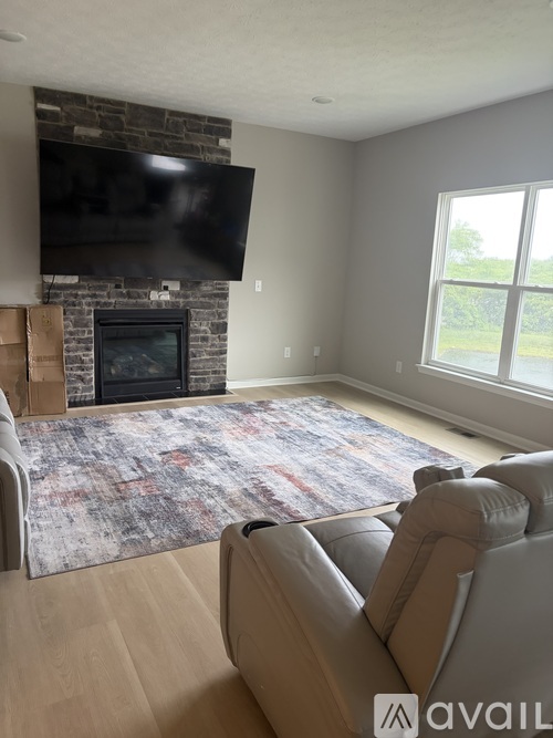 A living room with a stone fireplace and a flat screen TV mounted above it.