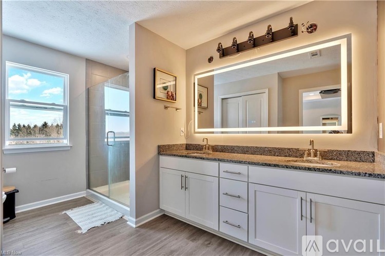 A bathroom with a large mirror, a sink, and a window with a view of trees.