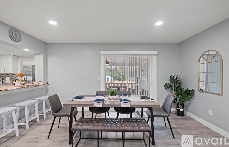 A dining room with a table set for four and a window with blinds.