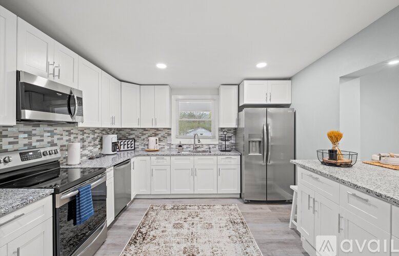 A modern kitchen with white cabinets and stainless steel appliances.