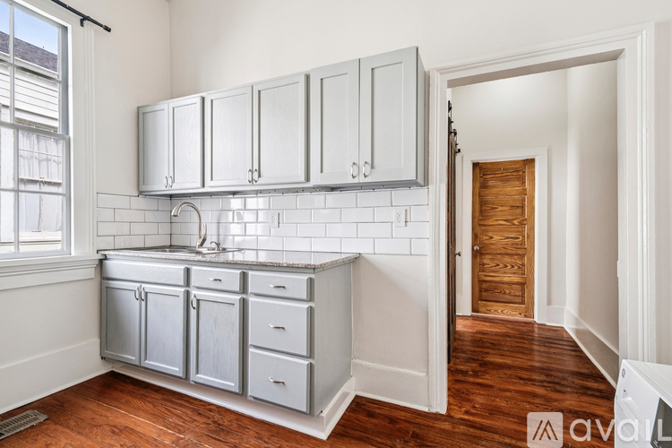 A kitchen with white cabinets and a wooden door.