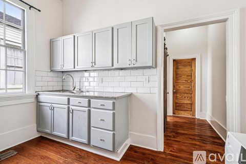 A kitchen with white cabinets and a wooden door.