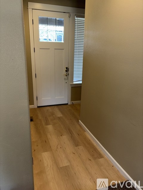 A white door with a window above it in a hallway.
