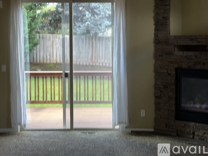 A room with a fireplace and sliding glass doors leading to a backyard.