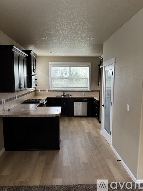 A kitchen with black cabinets and a wooden island.