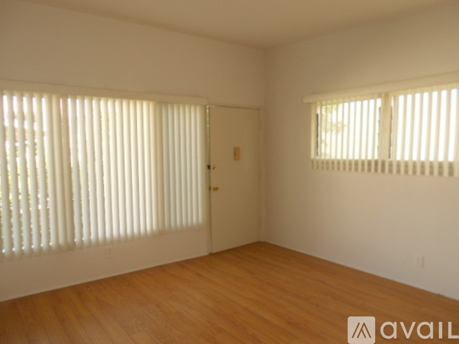 A room with wooden floors and two windows with blinds.