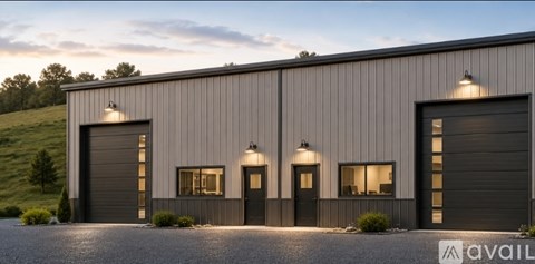 A modern building with a grey exterior and black garage doors.