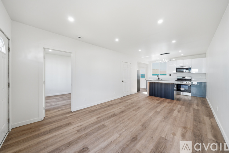 A spacious room with wooden flooring and white walls.