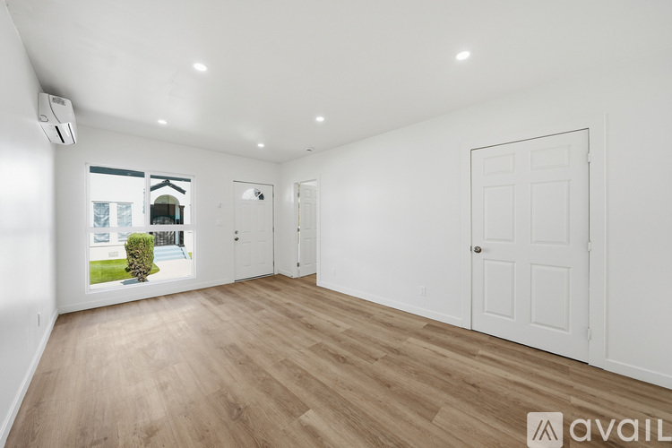 A spacious room with wooden flooring and white walls.