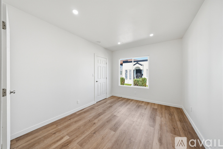 A room with wooden flooring and a window showing a view of a building outside.